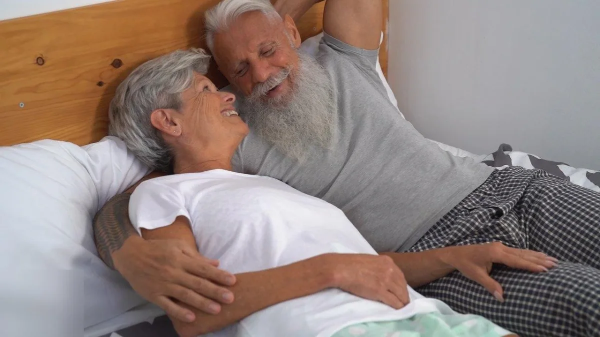 An older couple smiling together in bed