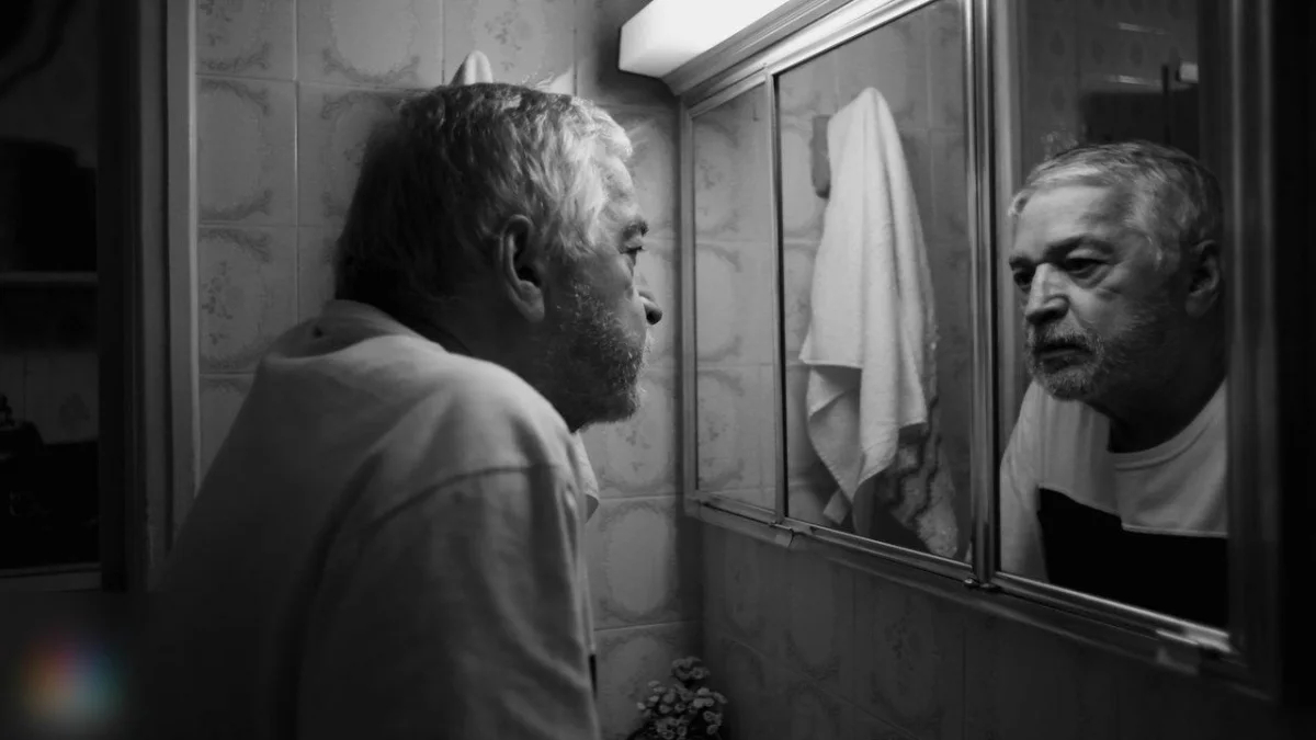 An older man looking at himself in the bathroom mirror